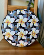 Handcrafted round vinyl bag in black floral vinyl with black hardware and hidden strap connectors.