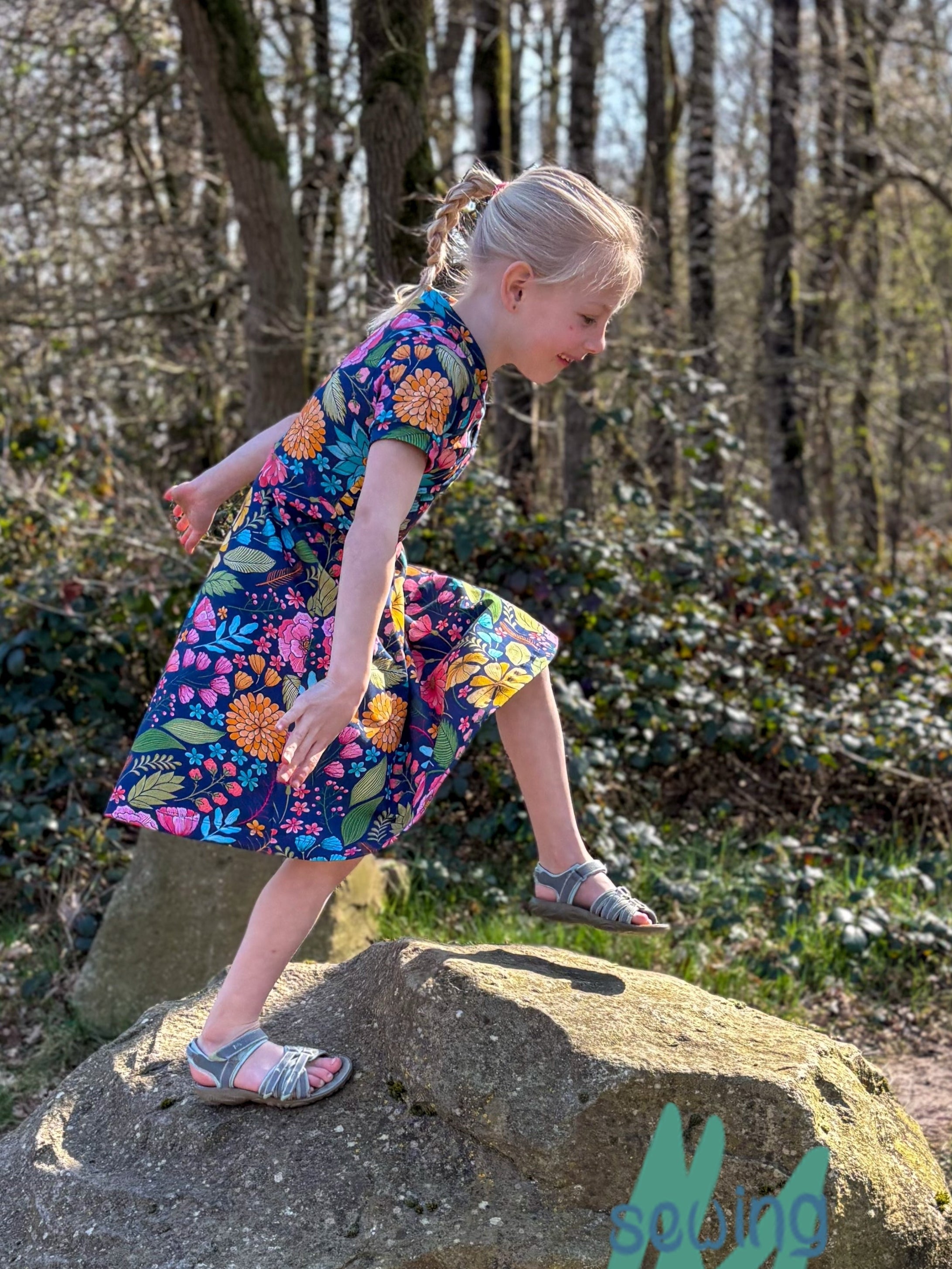 Floral fabric dress with faux wrap bodice and short sleeves. 1/2 Circle skirt with pockets. Toddler to teen sewing pattern.
