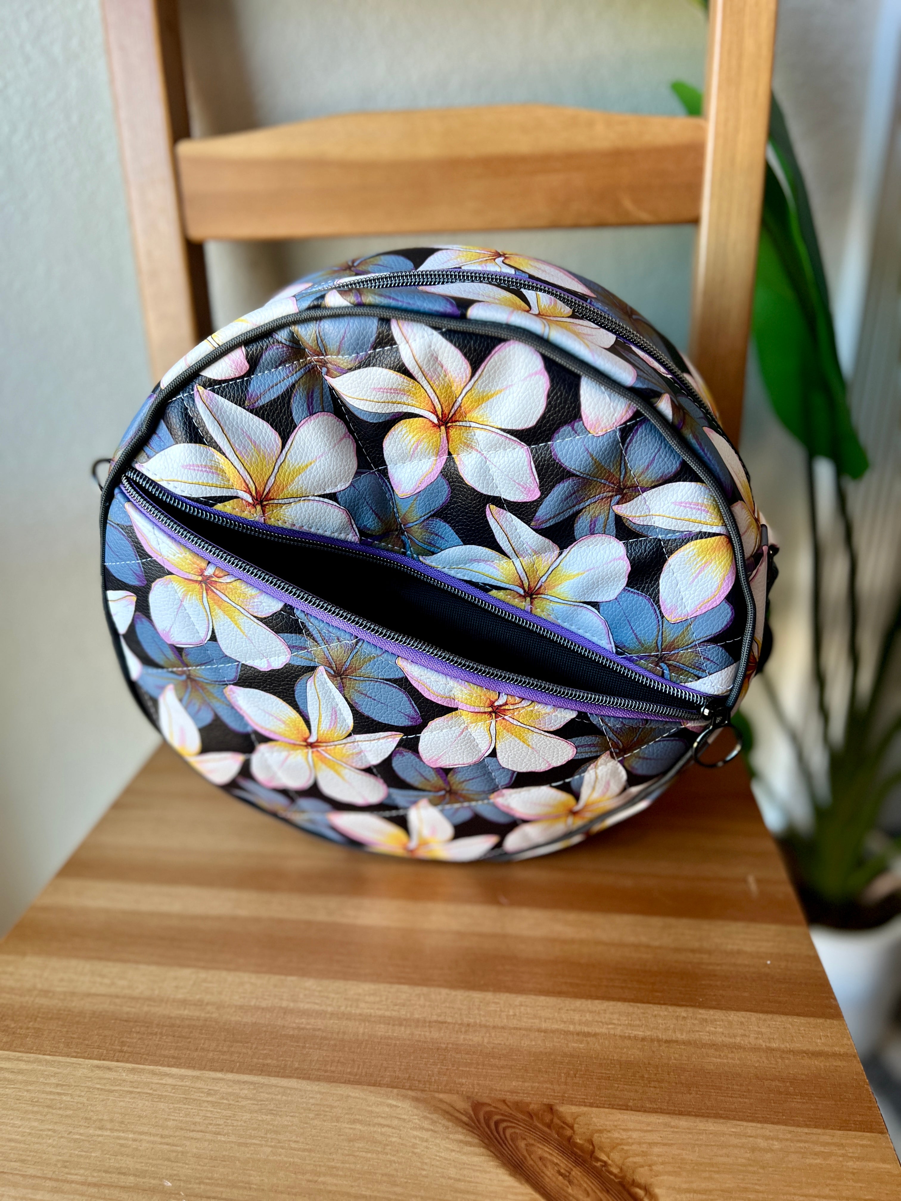 Handcrafted round vinyl bag in black quilted vinyl with black  hardware and hidden strap connectors.