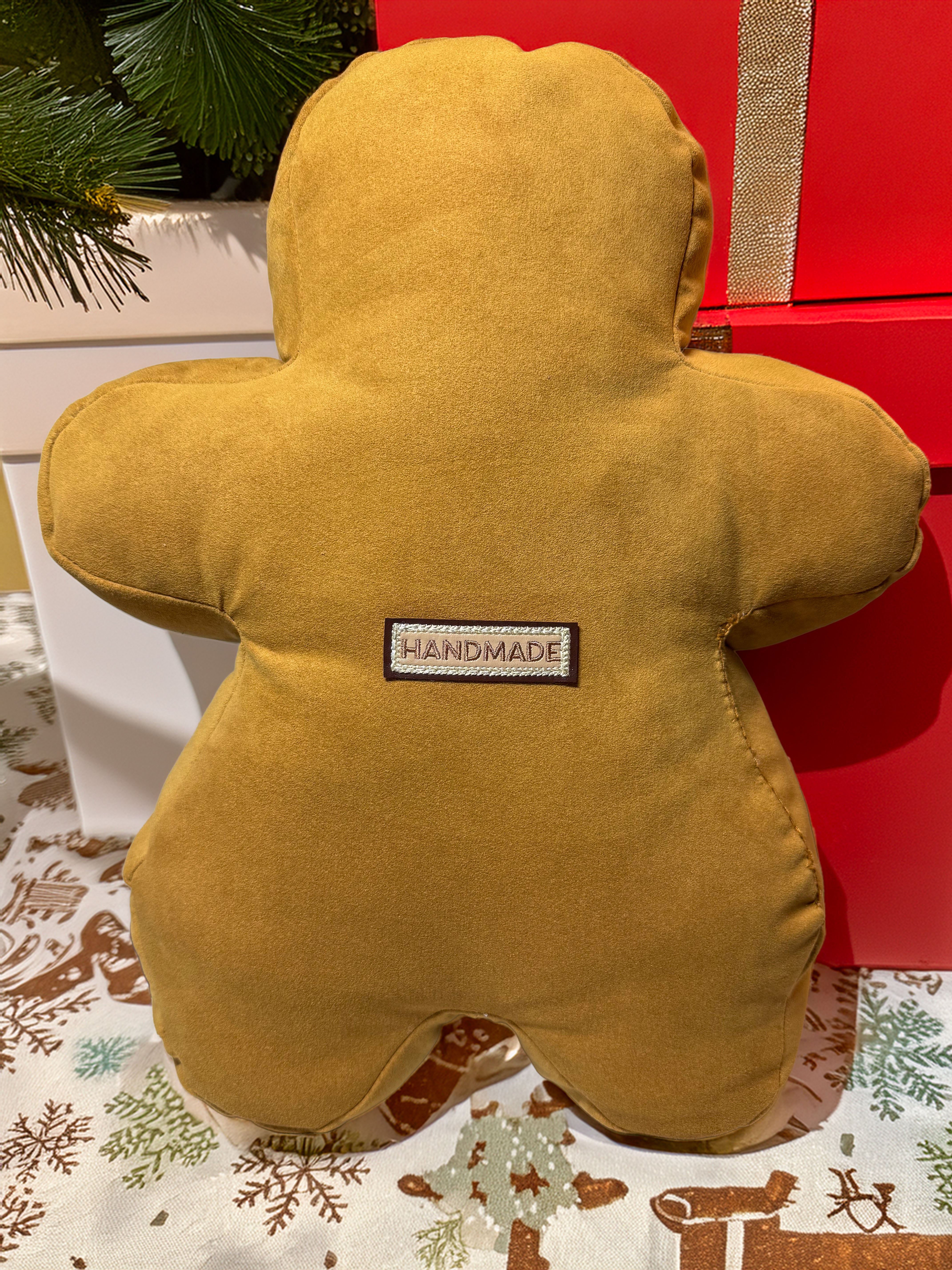 Yellow plush toy with a 'Handmade' label on a decorative surface with a red gift box in the background.