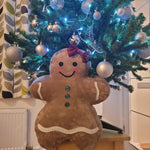 Jolly Gingerbread People Pillow styled beside a Christmas tree for holiday decorating.