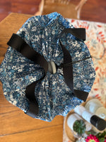 Top view of the blue floral fabric slow cooker carrier with black ribbon on a wooden surface. This carrier was made using the warm and cozy slow cooker carrier pattern by Ellie and Mac sewing patterns.