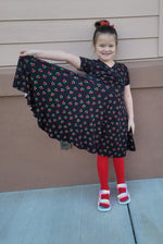Cherries fabric dress with faux wrap bodice and short sleeves. Circle skirt for twirling. Toddler to teen sewing pattern.