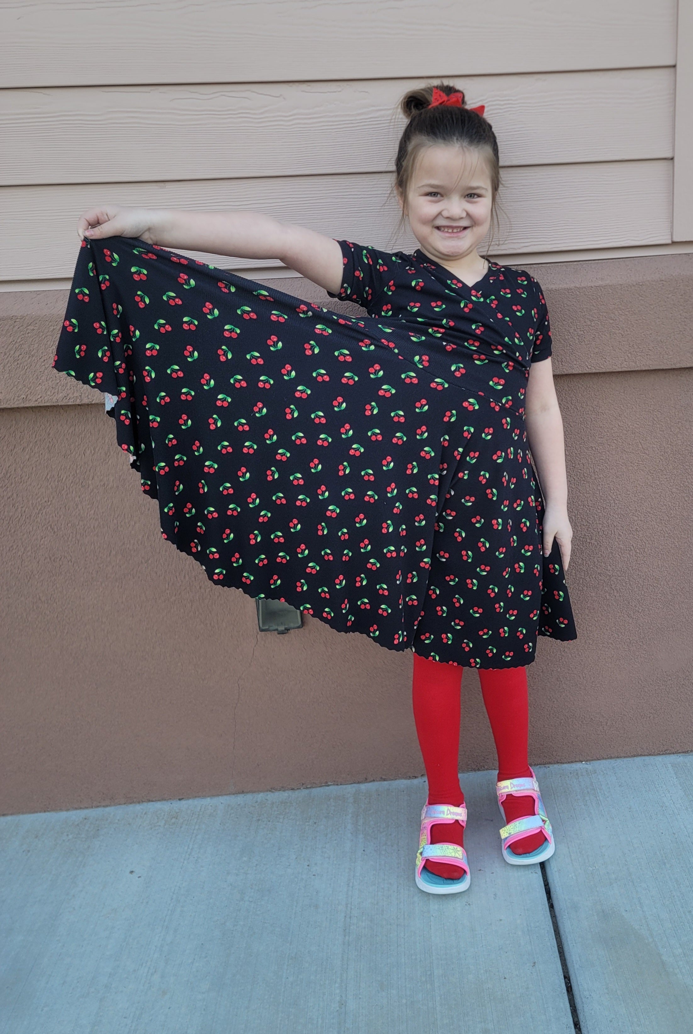 Cherries fabric dress with faux wrap bodice and short sleeves. Circle skirt for twirling. Toddler to teen sewing pattern.