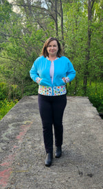 Woman on a path modeling a aqua and blue athletic bomber jacket with zip closure, kangaroo pocket detail, and cuffs. Easy pdf sewing pattern.