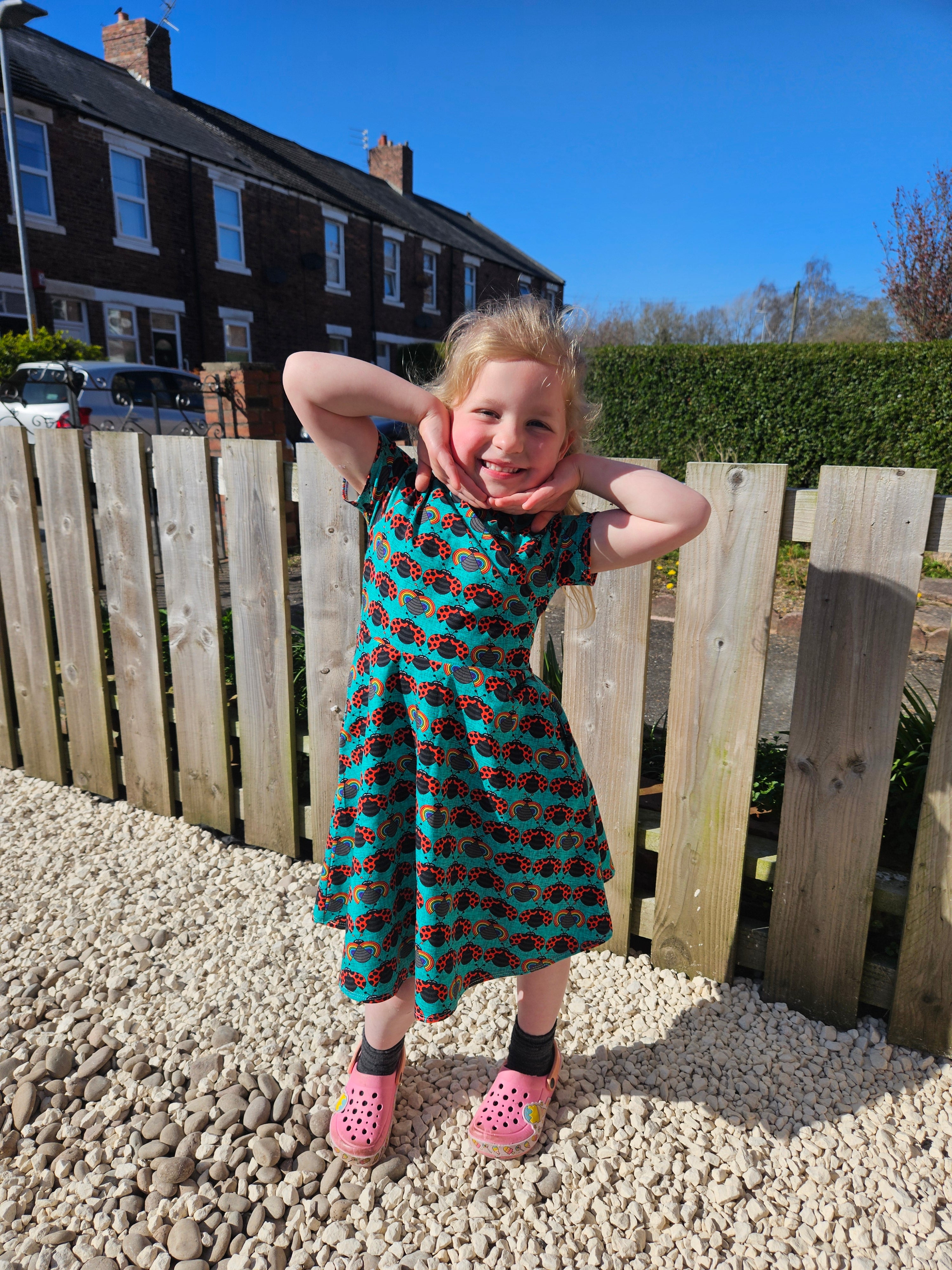 Ladybug fabric dress with faux wrap bodice and short sleeves. Circle skirt for twirling. Toddler to teen sewing pattern.