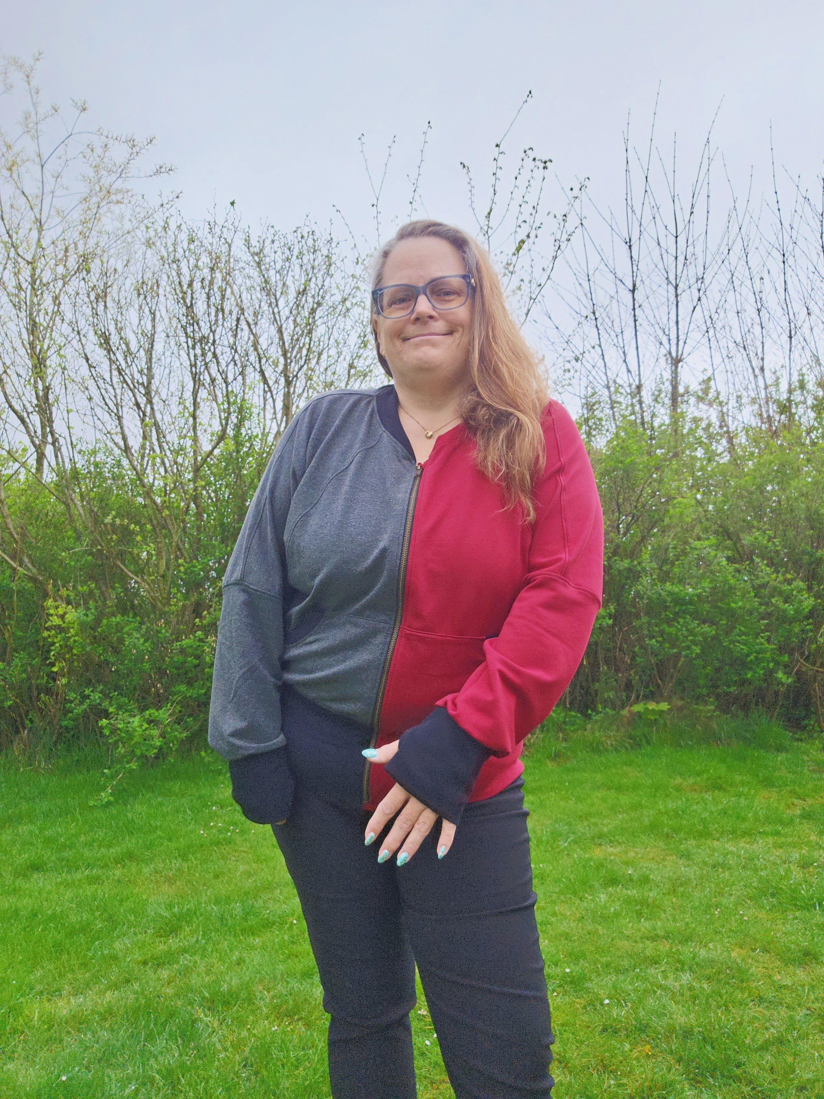 Model wearing a color-block knit fabric zip-up athletic jacket with raglan dolman sleeves, kangaroo pocket, and curved waistband. Knit fabric sewing pattern - instant download. High Hip Length.