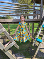 Sunflower fabric dress with faux wrap bodice and short sleeves. Circle skirt for twirling. Toddler to teen sewing pattern.