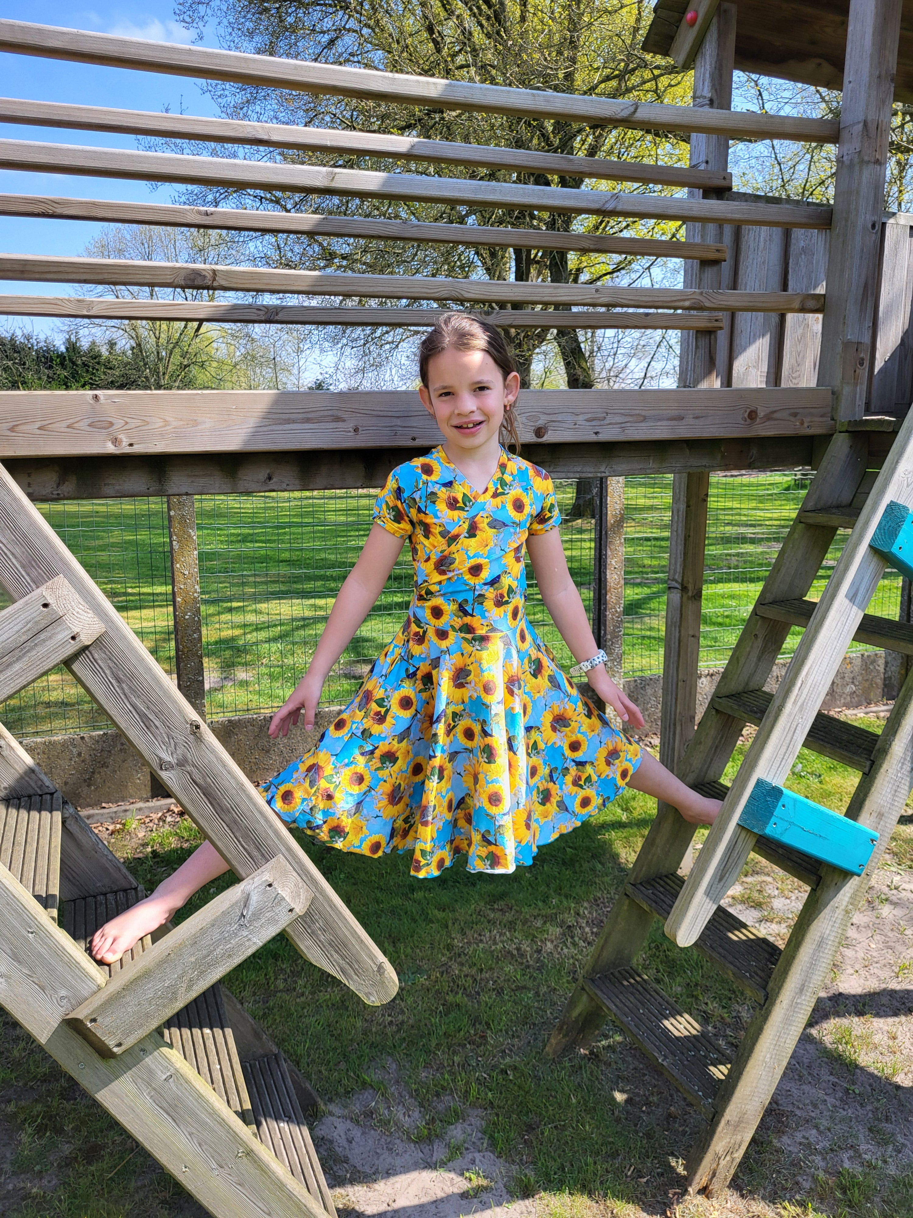 Sunflower fabric dress with faux wrap bodice and short sleeves. Circle skirt for twirling. Toddler to teen sewing pattern.