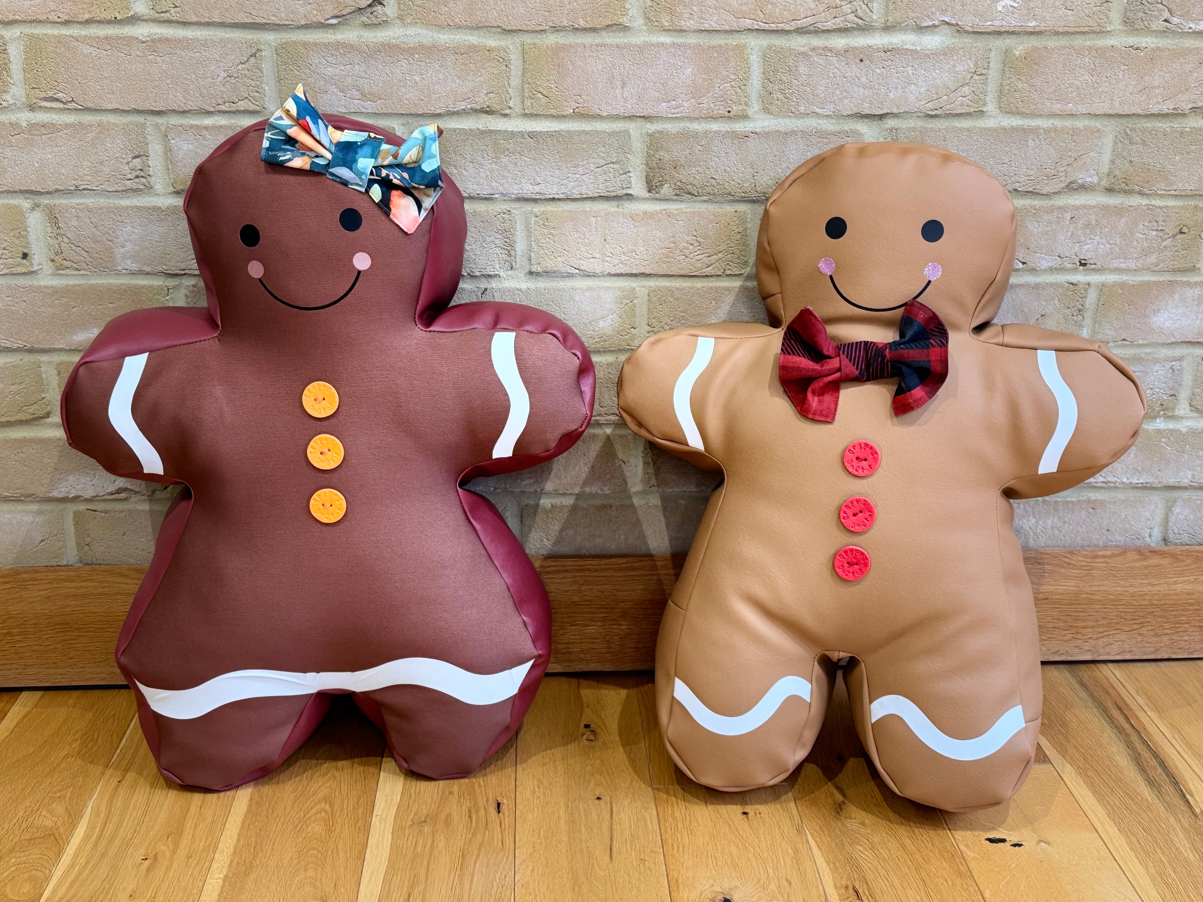 Two diy holiday gingerbread-themed plush toys against a brick wall.