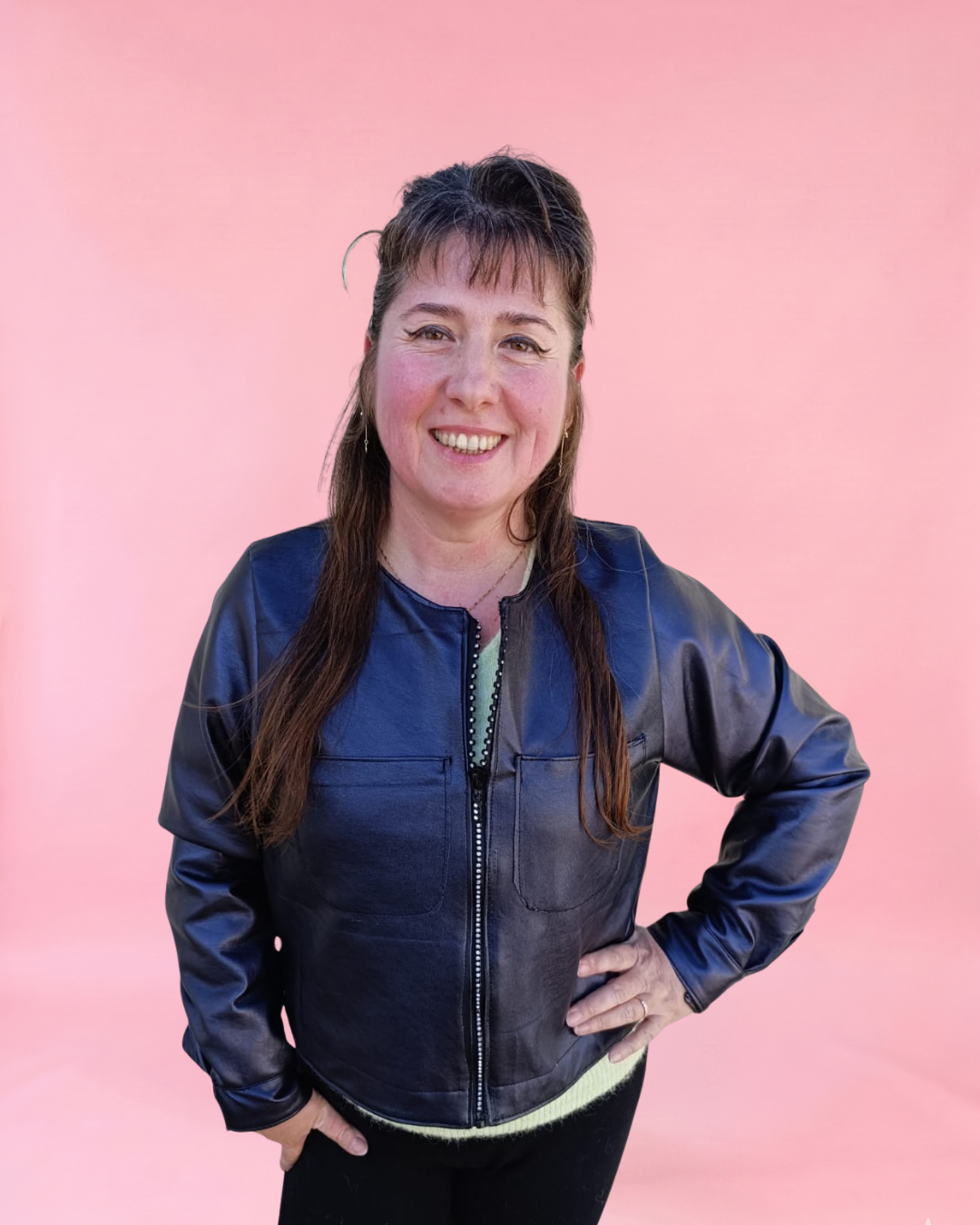 Person wearing a black leather jacket against a pink background. Trendy sewing patterns 