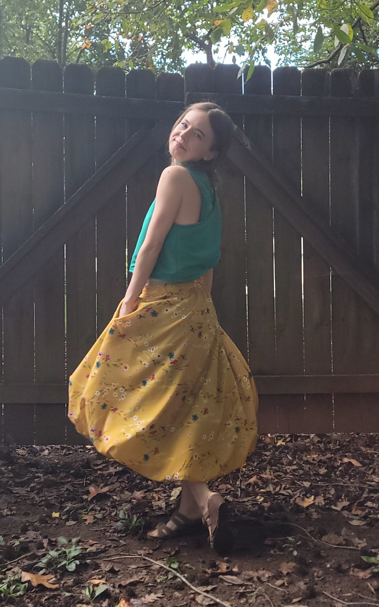 Person wearing a yellow bubble skirt with black patterns in an outdoor setting.