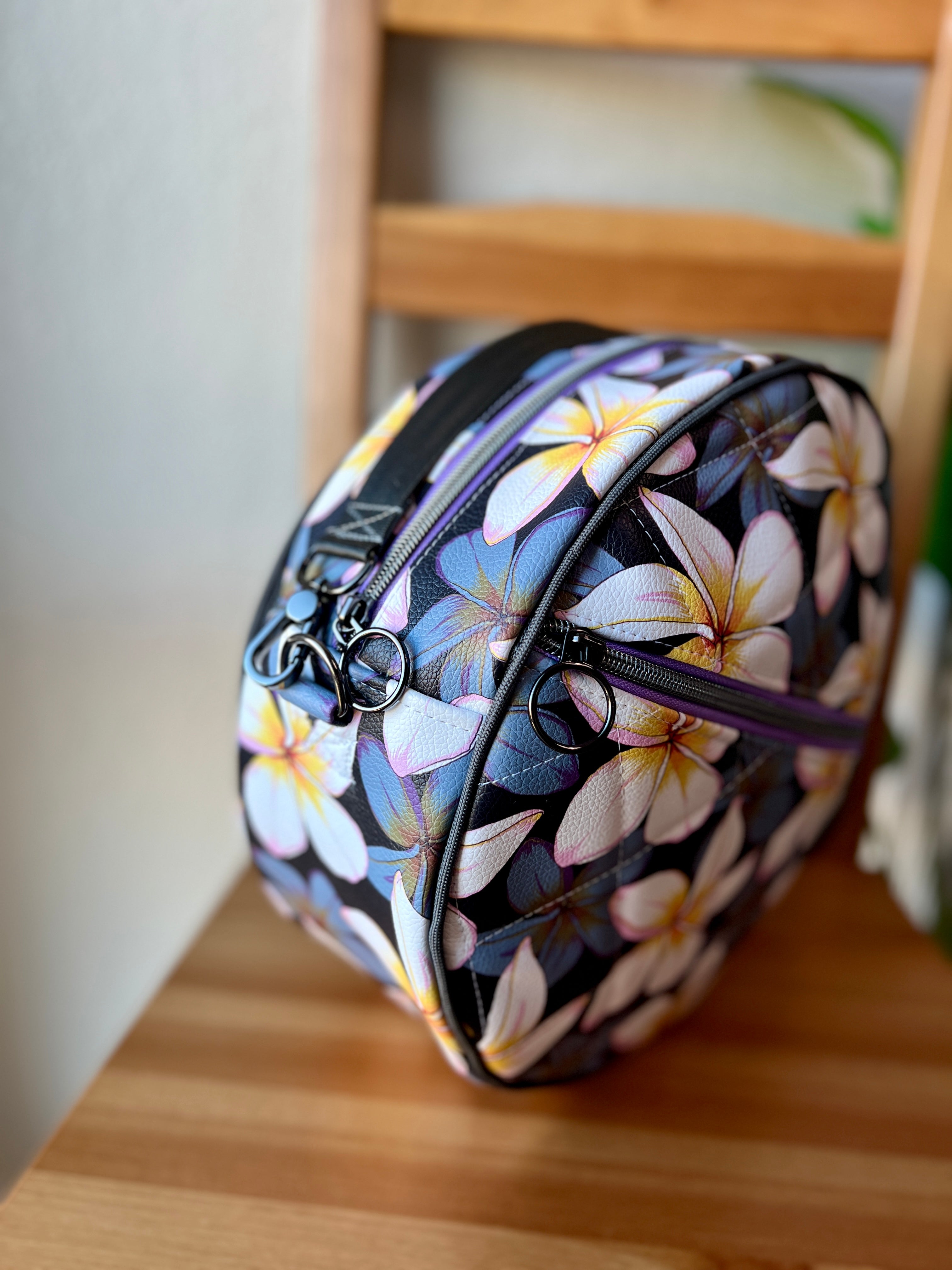 Floral-patterned round bag on a wooden surface. Side view.