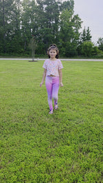 Girl modeling pink crop top and ombre pink to purple leggings. Her hair is in a ponytail and she is walking toward the camera.