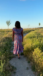 Video of a beautiful woman wearing a midi length tiered dress with shirred waist and short puff cap sleeves. 