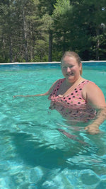 Woman showing tropical twist swimsuit sewing pattern on and in pool.