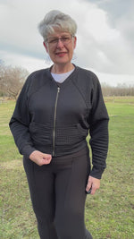 Woman outside in a park modeling a black textured fabric knit bomber jacket with zip closure. Athletic Cropped version. Ellie and Mac PDF sewing patterns.