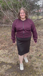 Woman outside modeling a burgundy and black houndstooth athletic bomber jacket with zip closure, kangaroo pocket detail, and thumbhole cuffs. Easy pdf sewing pattern.