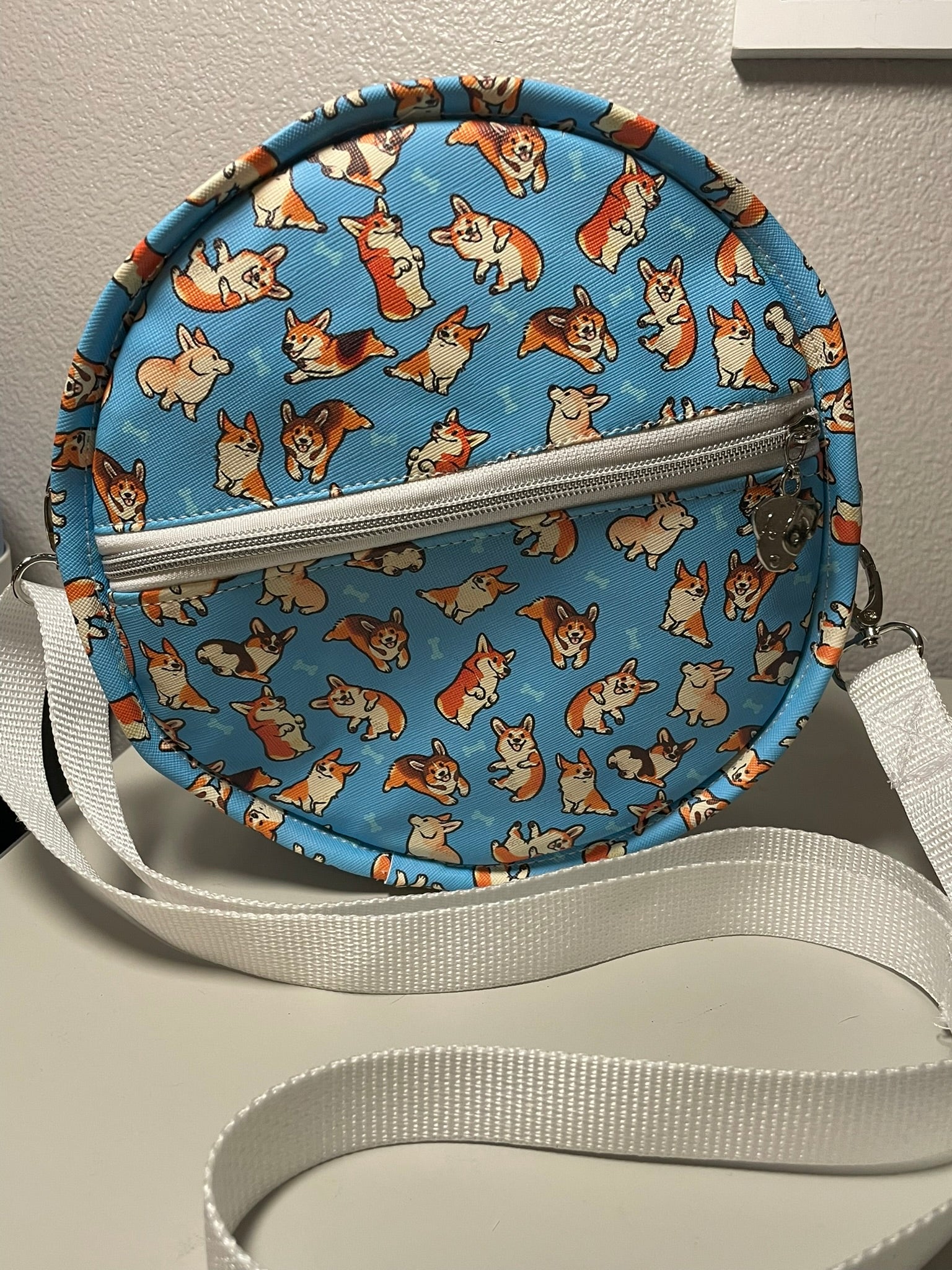 Round crossbody bag with corgi pattern on a flat surface