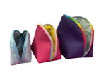 Three colorful Tessa zippered pouches on a white background. Small, medium, and Large. 