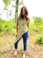 Ellie & Mac Asymmetrical Cinch Top Sewing Pattern. The image features a person modeling the finished in a ditsy floral print, worn with jeans. It is showcasing the asymmetrical hem and cinched side detail. This PDF sewing pattern is available in sizes XXS-6XL and includes projector files and a video sew-along tutorial. Printable on A4, A0, and Letter paper sizes.