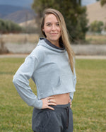 Woman wearing a cropped sweatshirt with hood and kangaroo pocket.