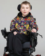 Boy in wheelchair wearing a colorful long sleeve sweater with hood. Sewn using Ellie & Mac sewing patterns.