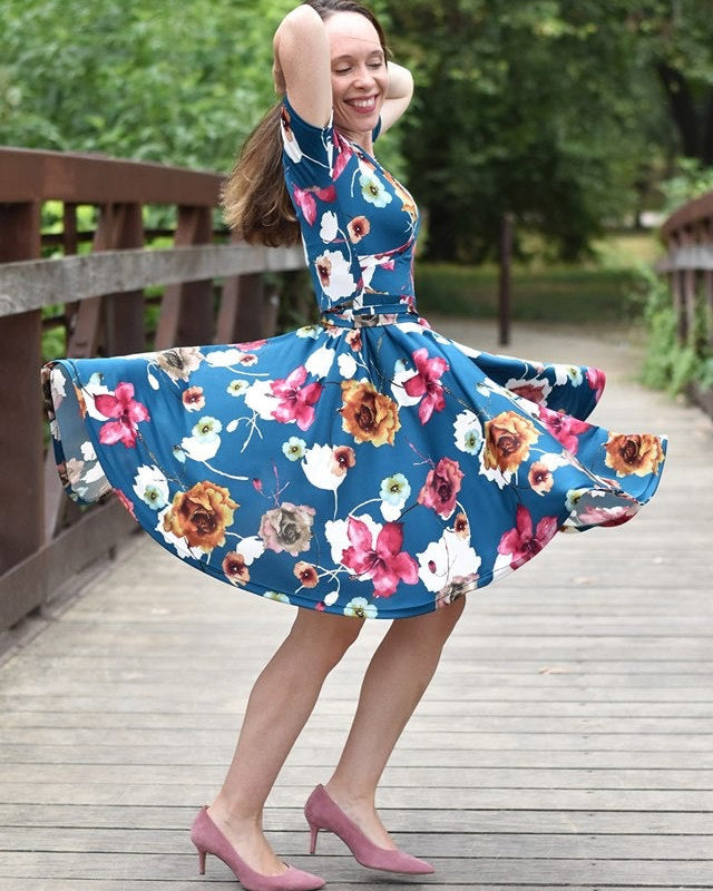 Woman twirling in a floral dress on a wooden bridge