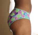 Woman wearing a heart print pair of mid-rise panties made using the Feel Frisky Panties sewing pattern by Ellie and Mac sewing patterns. Easy digital sewing pattern for beginners. Use a sewing machine and/or serger and knit fabric.