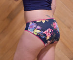 Woman wearing a navy tee and floral panties made using the Feel Frisky Sewing Pattern. Great for using up fabric scraps, upcycling old clothing, and making underwear that fit you perfectly.