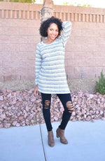 Women wearing a white with black striped sweater with raglan sleeves and crew neckline. 