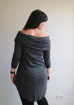 back view of the slouchy cowl neck dress with 3/4 sleeves and curved hem. Model is wearing black leggings underneath.