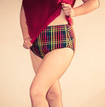 Woman wearing a red t-shirt and colorful plaid high-rise panties with black picot elastic. Full-coverage panties that flatter and are comfortable to wear. These panties do not ride up. Easily sew them with the Ellie and Mac Feel Frisky Panties sewing pattern. Digital PDF sewing pattern with instant download. 