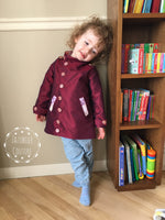 girl wearing a burgundy satin peacoat made using the Kids Duke Jacket Sewing pattern by ellie and mac patterns