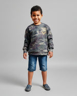 Boy wearing an oversized sweater made using Ellie and Mac sewing patterns for kids. Sweater knit fabric used in camo print.