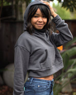 Woman wearing a grey oversized sweatshirt with hood and kangaroo pocket.
