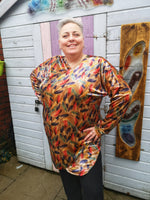 Woman wearing a velvet crossover sweater with feather print standing outside.