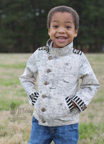 Ellie & Mac Kids Duke Jacket sewing pattern worn by a smiling boy. The jacket is made in navigation themed fabric with stripe accents.