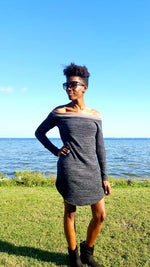 A woman with black hair standing outside in front of a gorgeous body of water wearing a sweater dress with long cuffed sleeves. Hem of the sweater is hemmed and curved. Made using Ellie and Mac Sewing Patterns.